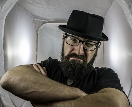 A bearded and angry looking man, looking like a doorkeeper with black glasses Stock Photos