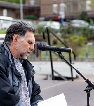 Bearded and gray-haired man speaks in front of microphone Stock Photos