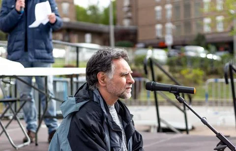 Bearded and gray-haired man speaks in front of microphone Stock Photos