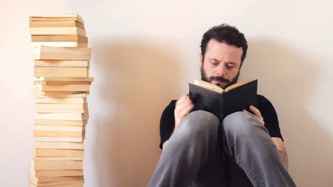Bearded and handsome man licks finger and turns the page Stock Footage 128299526