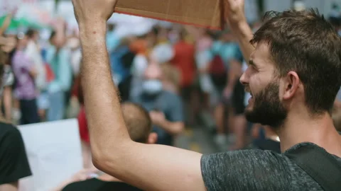 Bearded angry guy with poster sign shouts in crowd of political strike activists Stock Footage 160978073