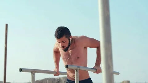 Bearded athlete in headphones pressing on parallel bars. Power training Stock-Footage 79187779