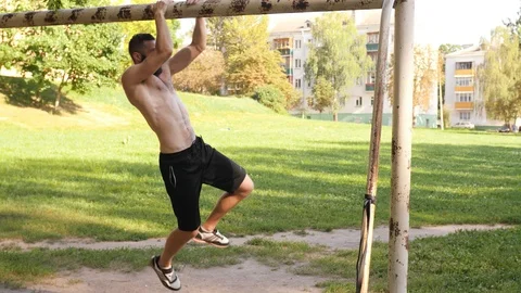Bearded athlete making pull-up exercisings on a crossbar of football goal. 4K Stock Footage 99162249