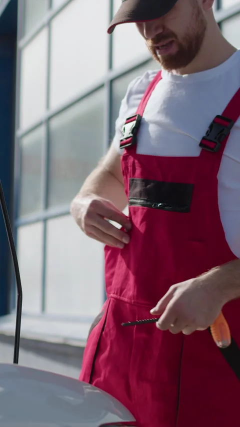 Bearded auto mechanic while repairing something under the hood of the customer's Stock Footage 276347900