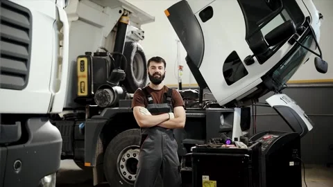 Bearded auto technician posing with arms crossed in front of an open-cab truck Stock Footage 333705839