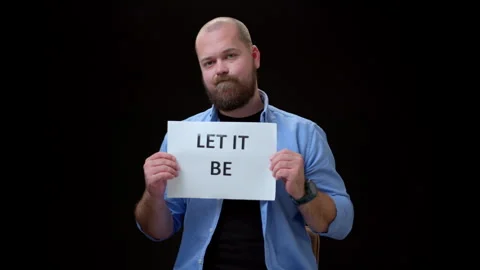 Bearded bald man in a blue shirt shows a piece of paper with the inscription LET Stock Footage 274505259