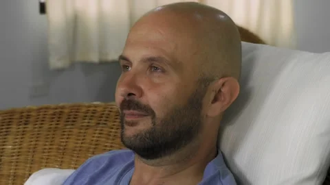 A bearded bald man is lying on the couch, watching TV and laughing. Close-up Vídeo Stock 145315740