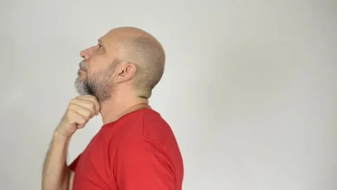 Bearded, bald man wearing a red shirt, walks thoughtfully touching his beard. Stock Footage 272924617