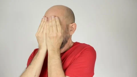 Bearded, bald man wearing red shirt shakes his head with both hands on his .. Stock Footage 272924628