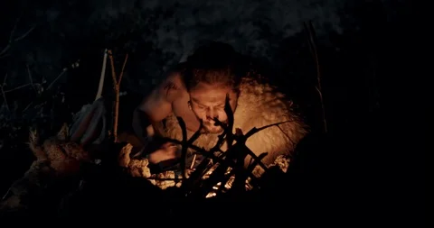 Bearded barbarian making fire at night Stock Footage 130010219