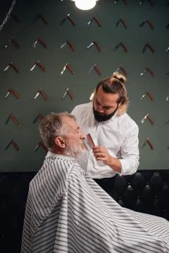 Bearded barber brushing old man's hair Stock Photos