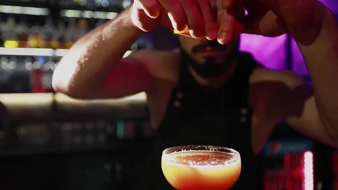 Bearded barman squeezes juice from an orange into a cocktail. Stock Footage 103372098