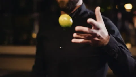 Bearded bartender in black shirt throws a lemon from hand to hand Stock Footage 144002917
