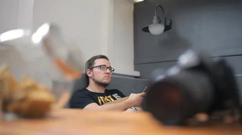 Bearded brunet sits on gray sofa in art studio Video stock 65786591