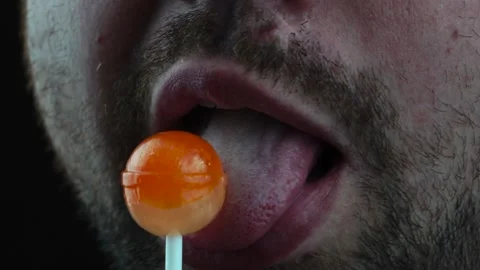 Bearded brutal man licks candy on a stick simulating oral sex Stock Footage 130222196