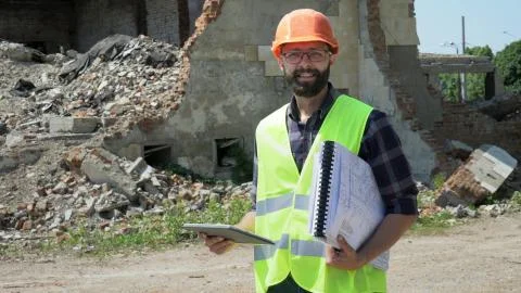 Bearded builder engineer with a tablet and drawings smiling and looking at the Stock Photos