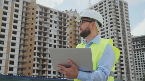 Bearded building inspector working on laptop at construction site Stock Footage 219874881