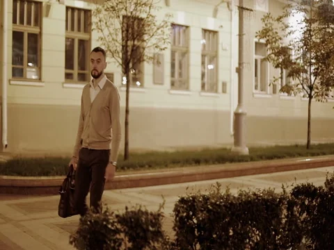 A bearded businessman in a beige jacket with a bag in his hand walks through the Stock Footage 80052341