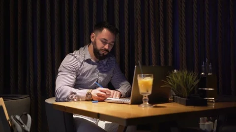Bearded Businessman taking notes with pen while working at home on laptop Stock Footage 120562493