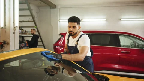 Bearded car wash worker man, wearing protective gloves, cleaning luxury modern Stock Footage 233820772
