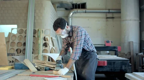 Bearded carpenter in safety glasses working with electric planer in workshop 스톡 동영상 66330169