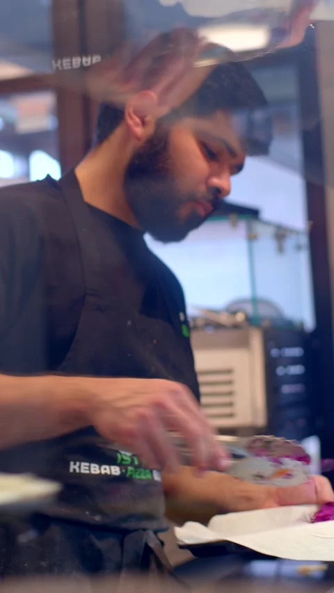 Bearded chef plating a colorful dish in a busy commercial kitchen Stock Footage 336534442