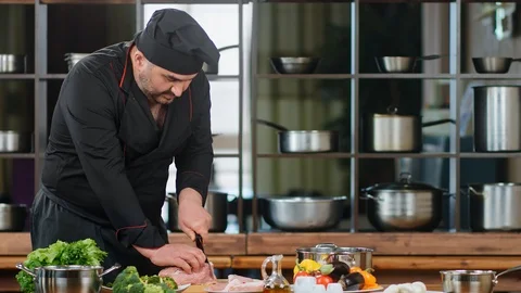 Bearded chef in uniform chopping delicate meat fillet. Medium shot on RED camera Stock Footage 124157185