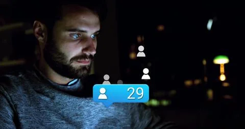 Bearded coder navigating user icons and blue notification bubble on laptop at Stock Photos