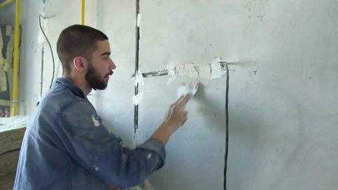 Bearded contractor spreading plaster on wire trunking Stock Footage 154461173