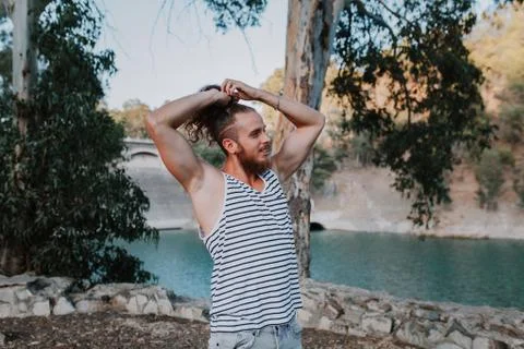 Bearded cool man making himself a long hair pony in nature. Stock Photos