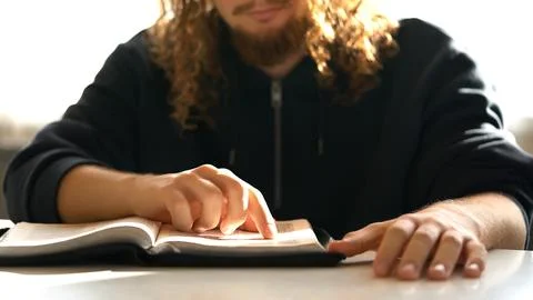 A bearded curly-haired man reads the Christian Bible, reading the word of God Photos