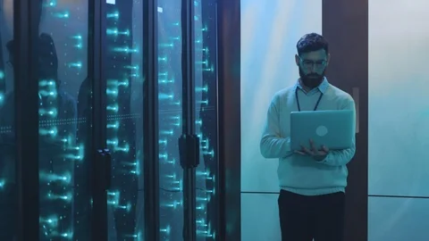Bearded data center server administrator holding laptop computer inspecting Stock Footage 119232925