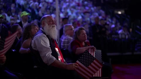 A bearded delegate holding an American flag listens to the speech Stock-Footage 345271644