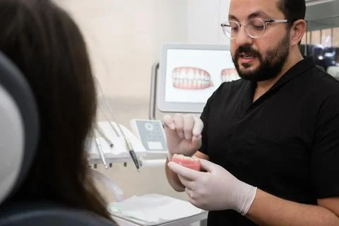 Bearded dentist with glasses explaining teeth treatment plan to patient during Stock-Fotos