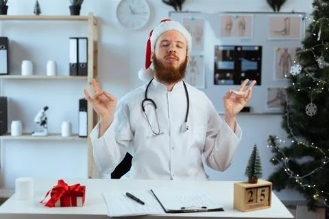 Bearded Doctor on the shift practicing mindfulness meditation while working on Stock Photos