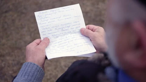 Bearded elderly man reads handwritten letter from daughter Stock Footage 230038048
