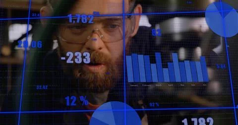 Bearded engineer with goggles analyzing data in lab, with bar chart and pie Foto stock