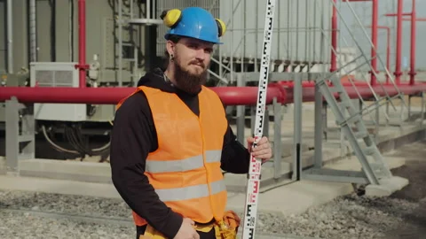 Bearded engineer holds geodetic pole posing at power station Stock Footage 142968659