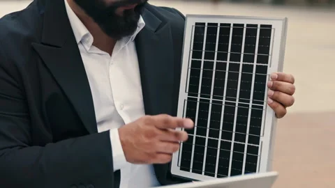 Bearded engineer in office suit displays solar panel during video call via Stock Footage 311932736