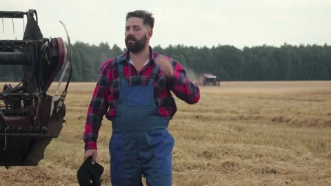 Bearded farmer in overalls on the background of working combine harvesters Vídeos de archivo 138850220
