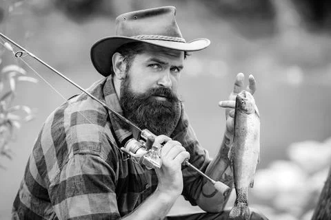 Bearded fisher in water. Young man fishing. Successful fly fishing