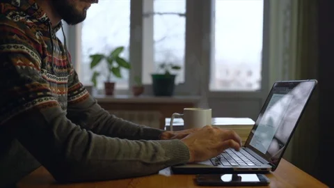 Bearded freelancer is drinking a tea in front of laptop at his home while work. Stock Footage 127257137