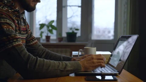 Bearded freelancer is working on laptop at his home, writing a text on screen. Stock Footage 127257209