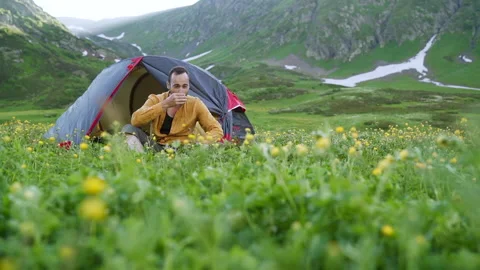 Bearded funny man with mug of coffee near tent at mountains Stock Footage 152539909