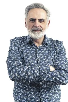 Bearded grey-haired man in a blue patterned button-up shirt with serious stance Stock Photos