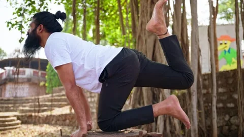 Bearded guy balances on one knee with a raised leg Stock Footage 303127461