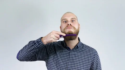 The bearded guy with the bald head combing his beard  in front of the mirror. Stock Footage 122005520