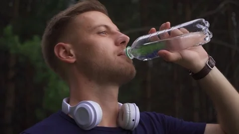 Bearded guy drinking water at a jog Stock Footage 220343218
