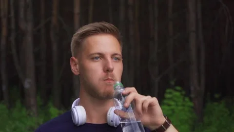 Bearded guy drinking water at a jog Stock Footage 221399534