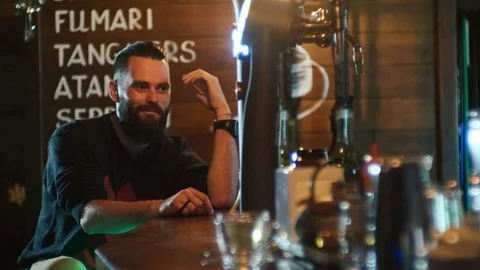 Bearded guy drinks a cocktail and communicates with the bartender at the bar Stock Footage 87783394